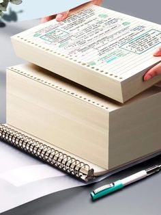 two books stacked on top of each other next to a pen and notebook with writing