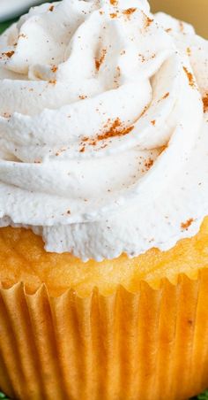 a cupcake topped with whipped cream on a green cloth covered plate next to a fork