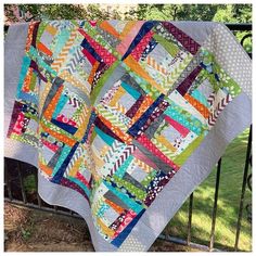 a colorful quilt is hanging on a fence