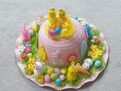 a pink hat decorated with easter eggs and small yellow chicks sitting on top of it