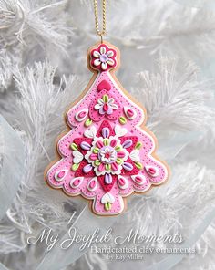 a pink christmas tree ornament hanging from a white christmas tree with snowflakes