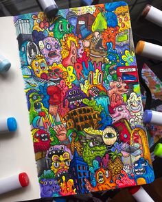 an art journal with markers and crayons next to it on top of a table