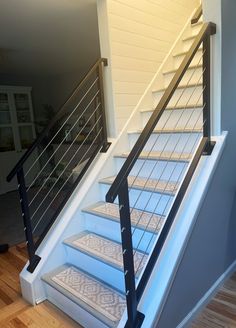 a set of stairs leading up to the second floor in a home with hardwood floors and white painted walls