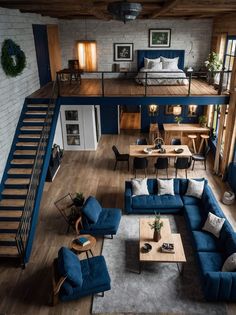 an overhead view of a living room with blue couches and wooden stairs leading up to the second floor