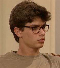 a young man wearing glasses sitting in a chair