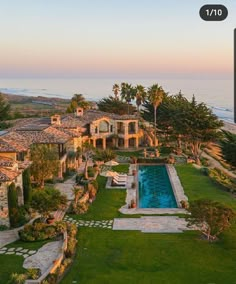 an aerial view of a house with a swimming pool in the foreground and ocean in the background