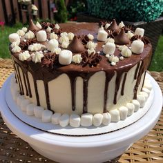 a chocolate cake with marshmallows on top sitting on a wicker table