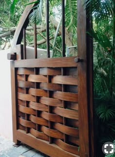 a wooden fence made out of squares and strips of wood in front of some plants