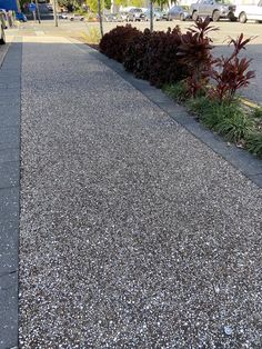 the sidewalk is lined with gravel and plants