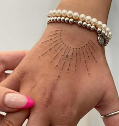 a woman's hand with a tattoo on it and some beads around the wrist