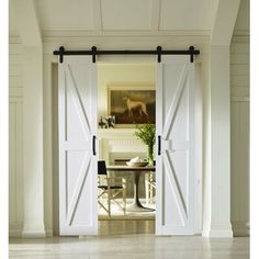 an open door leading to a dining room with white walls and wood flooring is shown