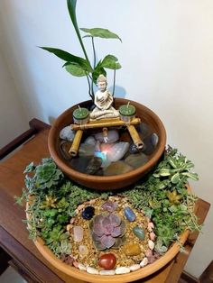 a potted plant sitting on top of a wooden table next to a buddha statue