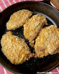 four fried meat patties in a skillet on a red and white checkered table cloth