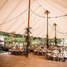 the inside of a large tent with tables and chairs set up for an outdoor function