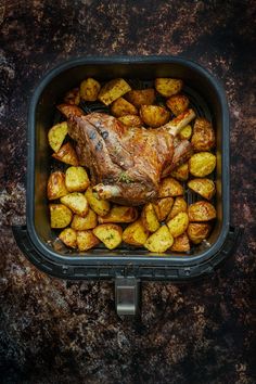 a roasting pan filled with potatoes and a piece of meat sitting on top of it