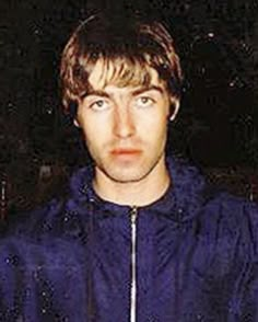 a young man in a blue jacket looking at the camera with an intense look on his face