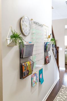 there is a wall with several calendars on it and a clock mounted to the wall