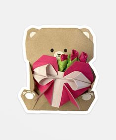 a brown teddy bear holding a pink heart shaped box with roses in it's lap