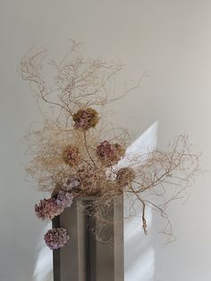 two metal vases with dried flowers in them