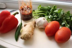 tomatoes, celery, garlic, and other vegetables are on a cutting board