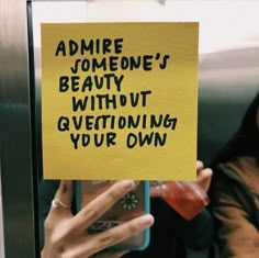 a woman holding up a yellow sign that says admire someone's beauty without questioning your own