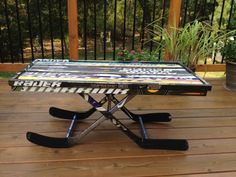 a table made out of skis on a wooden deck with plants in the background