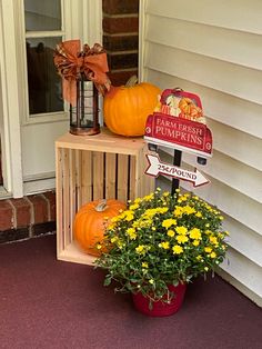 two pumpkins are sitting on top of a wooden stand with flowers and a sign