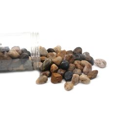 a jar filled with rocks sitting on top of a white floor next to a pile of stones