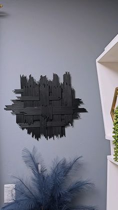 a wall hanging on the side of a gray wall next to a potted plant