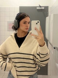 a woman wearing headphones taking a selfie in the bathroom