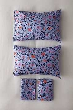 three pillows and two pillow cases on a white surface