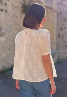 a woman standing in front of a stone building with her back turned to the camera