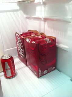 two cans of coca - cola sitting on top of an open refrigerator