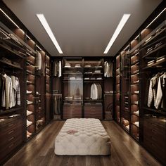 a large walk in closet with lots of clothes on the shelves and drawers, along with a footstool