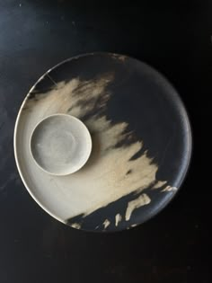 a black and white plate with a bowl on it sitting on top of a table