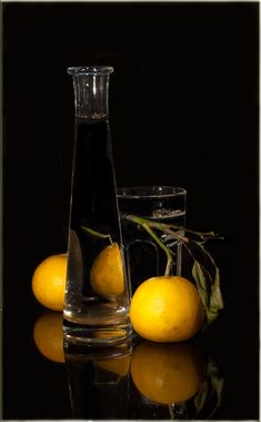 three lemons and two glass vases on a reflective surface