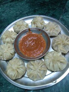 some dumplings are on a silver plate with sauce