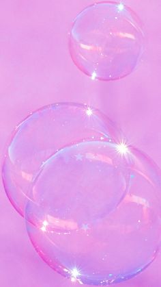 two soap bubbles floating in the air on a pink background