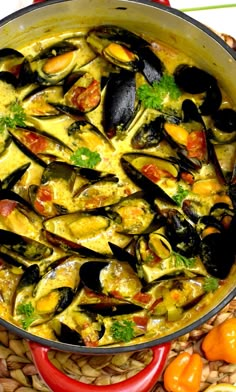 a pan filled with mussels and sauce on top of a table next to vegetables