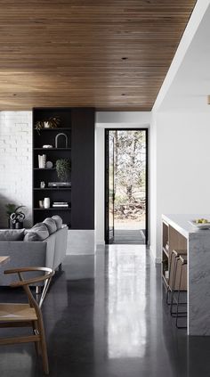 an open living room and dining area in a modern house with wood ceilinging, white walls