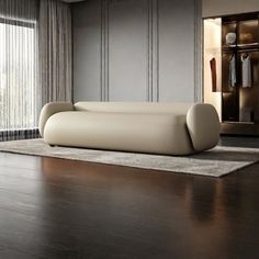 a large white couch sitting on top of a hard wood floor next to a window