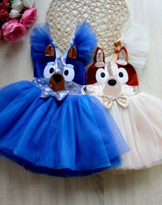 two little dogs wearing blue and white tutues on a table next to a straw hat