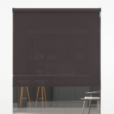 an empty room with two chairs and a large window covered in dark brown roller shades