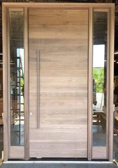 a modern wooden door with glass panels on the sides and side doors in front of it