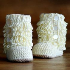 a pair of white crocheted baby booties with buttons