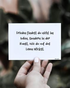 a person holding up a piece of paper with the words written in german on it