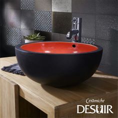 a black and red bowl sink sitting on top of a wooden counter next to a faucet