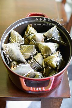 a pot filled with green leaves on top of a wooden table