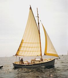 a sailboat with two people on it in the water