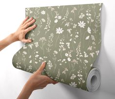 two hands holding onto a green floral wallpaper